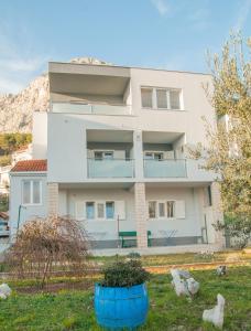 Uma casa branca com um vaso azul à frente. em Apartments Vulić em Omiš