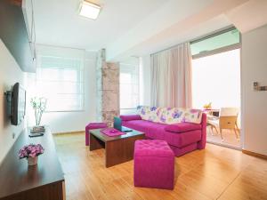 a living room with a purple couch and a table at Apartments Raymond in Sveti Stefan