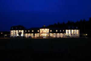 un grand bâtiment avec ses lumières allumées la nuit dans l'établissement Landhaus Lellichow, à Lellichow