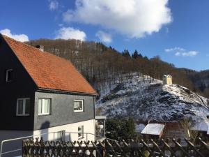 a house with a red roof next to a snow covered hill at Ferien Apartment Meister in Zorge