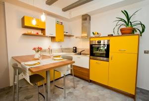 アヌシーにあるGite urbain AU 2BIS - Annecyのキッチン(黄色のキャビネット、木製テーブル付)