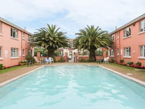 a large swimming pool in a courtyard with palm trees at 57 New Esplanade Court, Beach Close By Pool View in Paignton
