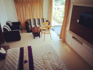 uma sala de estar com televisão e uma sala de estar com sofá em Swiss Cottage em Kodaikānāl