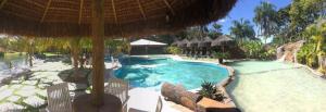 a swimming pool in a resort with an umbrella at Villa Triacca Hotel Vinícola & Spa in Brasília