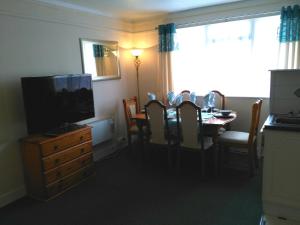 una sala da pranzo con TV e tavolo con sedie di 57 New Esplanade Court, Beach Close By Pool View a Paignton