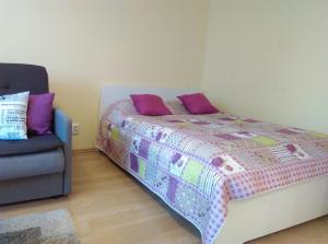 a bedroom with a bed with purple pillows and a couch at Gina's apartment Partizanu g in Kaunas