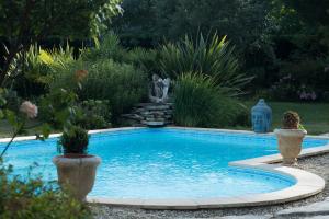 a swimming pool in a garden with two potted plants at Sur la route des châteaux du Médoc in Blanquefort