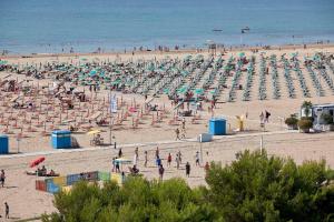 una playa con mucha gente y sombrillas en Villa Principe, en Bibione