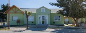 une maison verte et jaune dans une rue dans l'établissement Hosteria La casa de Ketty, à Puerto San Julian