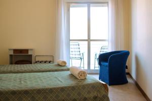 a room with two beds and a chair and a window at Hotel Il Girasole in Bova Marina