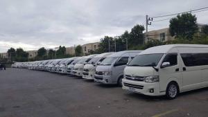 una fila de camionetas blancas estacionadas en un estacionamiento en Poppular Palace Don Mueang Bangkok, en Bangkok
