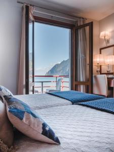 two beds in a room with a large window at Hotel Vila Bela in Porto da Cruz