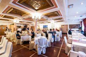 Menschen sitzen an Tischen in einem Restaurant mit weißen Tischen und Stühlen in der Unterkunft Hotel Touring in Livigno