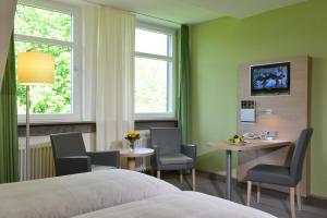 ヘスバッハにあるTagungszentrum Schmerlenbachのベッド、テーブル、椅子が備わるホテルルームです。
