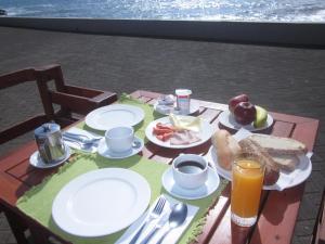 a table with plates of food and drinks on it at Hotel Vila Bela in Porto da Cruz