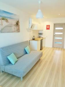 un divano blu in soggiorno con cucina di Hel_sky Apartament a Hel