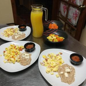 a table with three plates of food and a jar of orange juice at Hotel Posada Santa Fe in Ocotlán
