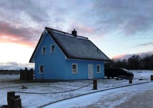 ein blaues Haus auf einem Feld mit Schnee auf dem Boden in der Unterkunft Haus "Kliffruhe" in Glowe