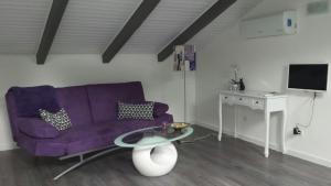 sala de estar con sofá púrpura y mesa en La Gatta Nera - The Black Cat en Bra