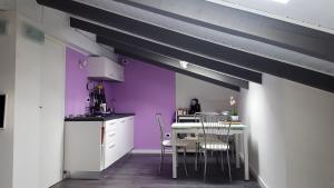eine Küche mit lilafarbenen Wänden sowie einem Tisch und Stühlen in der Unterkunft La Gatta Nera - The Black Cat in Bra