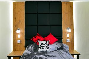 a bed with red pillows and a green headboard at Hyswan Self Catering Guesthouse in Krugersdorp