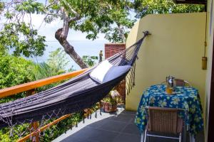 a hammock on the balcony of a house with a table at Pousada VillaBahia Morro in Morro de São Paulo +65 photos