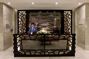 a man in a suit sitting at a desk in a lobby at Aswar Al Olaya Hotel Suites in Al Khobar