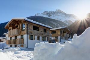 a house in the snow with the sun behind it at Chalet Bella in Pettneu am Arlberg