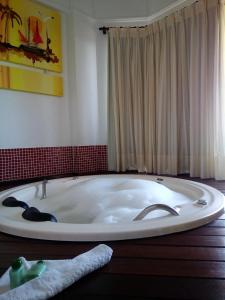 een bad in een kamer met een rode muur bij Raio do Sol Residence in Bombinhas