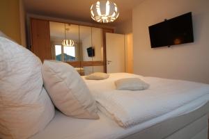 a bedroom with a white bed with pillows and a television at Wohnen am Yachthafen W45 in Cuxhaven