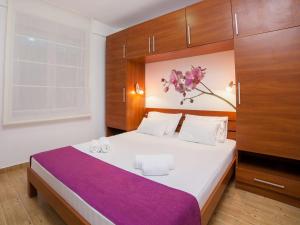 a bedroom with a large bed with a purple blanket at Apartments Raymond in Sveti Stefan