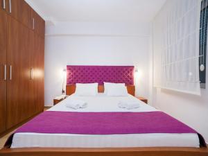 a bedroom with a large bed with a purple headboard at Apartments Raymond in Sveti Stefan