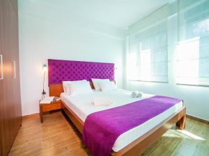 a bedroom with a large bed with a purple headboard at Apartments Raymond in Sveti Stefan