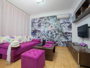 a living room with a purple couch and a tv at Apartments Raymond in Sveti Stefan