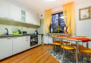 a kitchen with white cabinets and a table and chairs at Bucharest Pedestrian Old Town 3 Bedrooms by Orchid Garden in Bucharest