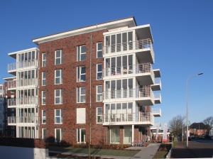 un edificio alto de ladrillo con balcones en una calle en Wohnen am Yachthafen W48, en Cuxhaven