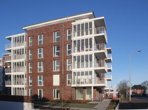 a tall brick building with balconies on a street at Wohnen am Yachthafen W48 in Cuxhaven