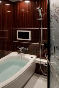 a bathroom with a tub and a tv on the wall at Third Place Hotel in Saitama