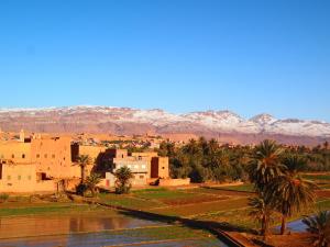 a village with palm trees and mountains in the background at Riad Al Anwar in Tinerhir
