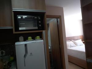 a small kitchen with a microwave and a refrigerator at Quarto particular (24m²) - 03 pessoas in Pedra Azul