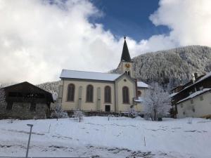 eine kleine Kirche mit einem Kirchturm im Schnee in der Unterkunft Ferienhaus Büsch in Gaschurn