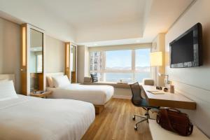 a hotel room with two beds and a desk and a television at Jen Hong Kong by Shangri-La in Hong Kong