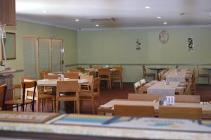 une salle à manger avec des tables et des chaises ainsi qu'une salle remplie de tables et de chaises dans l'établissement Heritage Resort, à Weipa