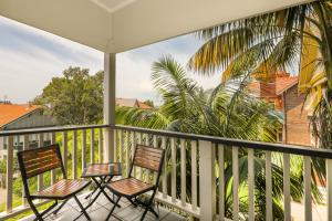 a balcony with two chairs and a palm tree at Glenferrie Lodge in Sydney