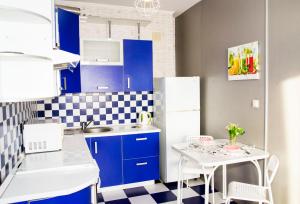 cocina con armarios azules y nevera blanca en RENT-сервис Apartment Zhukova 144 en Omsk