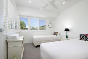 a white bedroom with two beds and a window at Noosa Haven Apt 12 Riverfront Elegance in Noosaville +18 photos