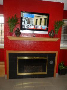 a fireplace with a tv on a red wall at Budgetel Inn Houston/Nasa in Webster