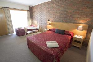 a bedroom with a bed and a brick wall at Horsham Country City Motor Inn in Horsham +39 photos