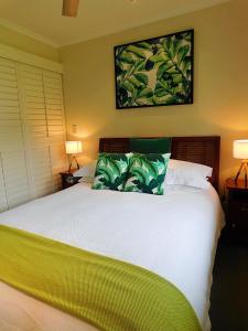 a bedroom with a large white bed with green pillows at Watersons at Airlie Central Apartments in Airlie Beach