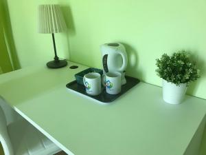 una mesa con dos tazas y una lámpara y una planta en Color House Malpensa B&B, en Cassano Magnago
